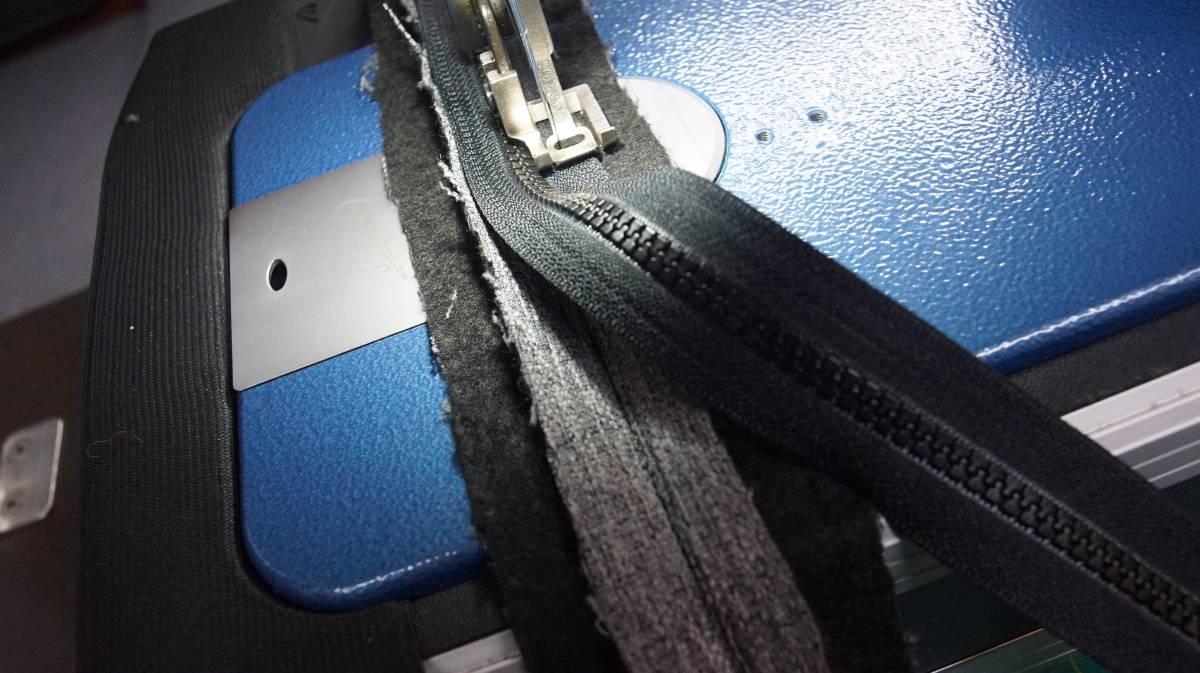 the zipper being sown onto the strip of fabric with a sewing machine