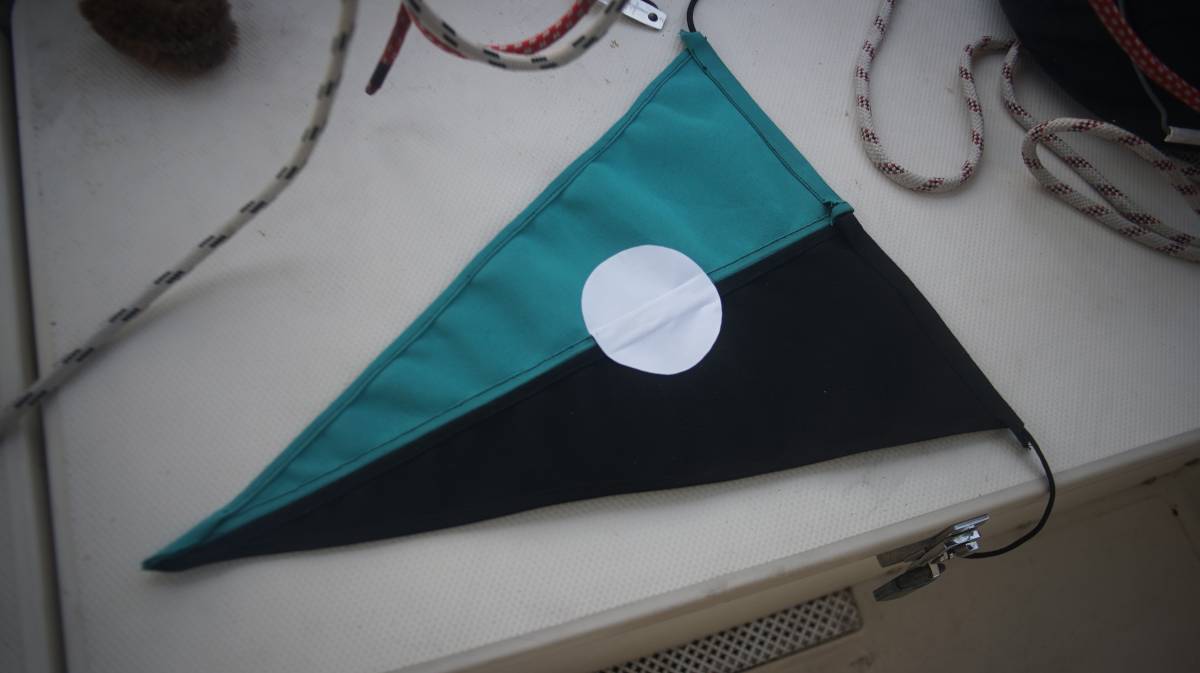 a cyan and black burgee with a white circle in the center