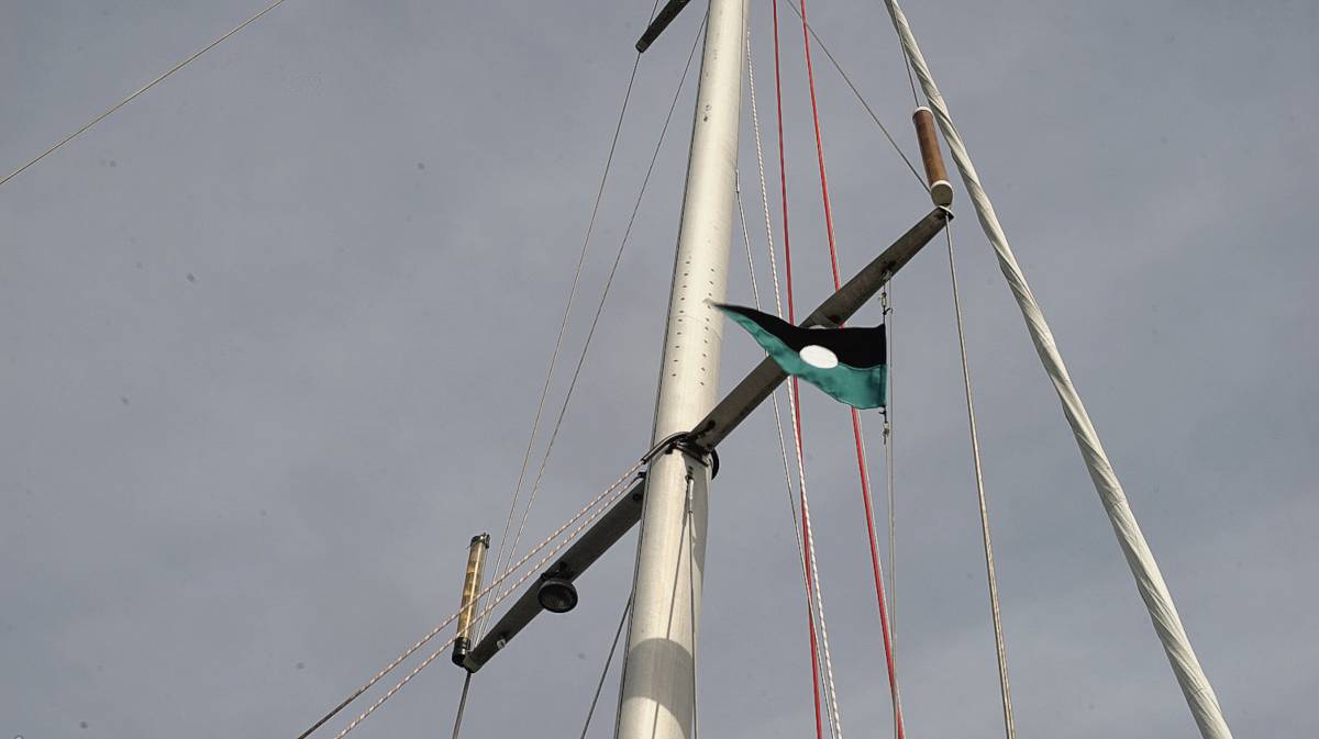a cyan and black burgee with a white circle in the center flying on the starboard side halyard of a sailboat