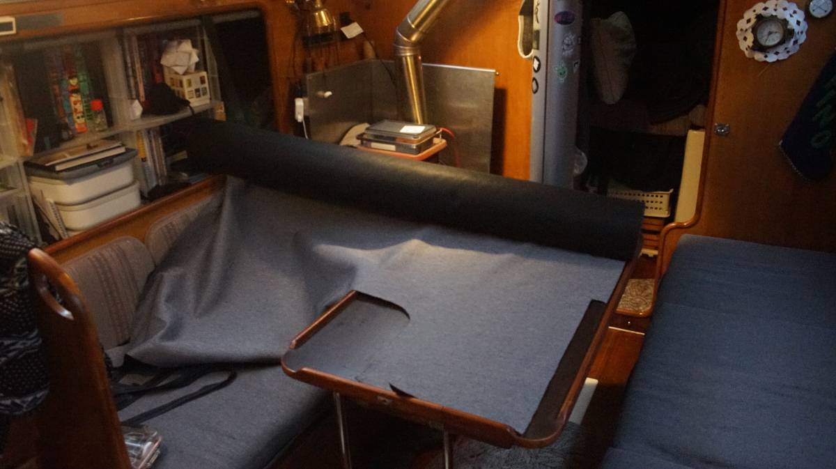 a giant roll of fabric sitting on the tiny saloon table, with the left end wedged into a bookshelf
