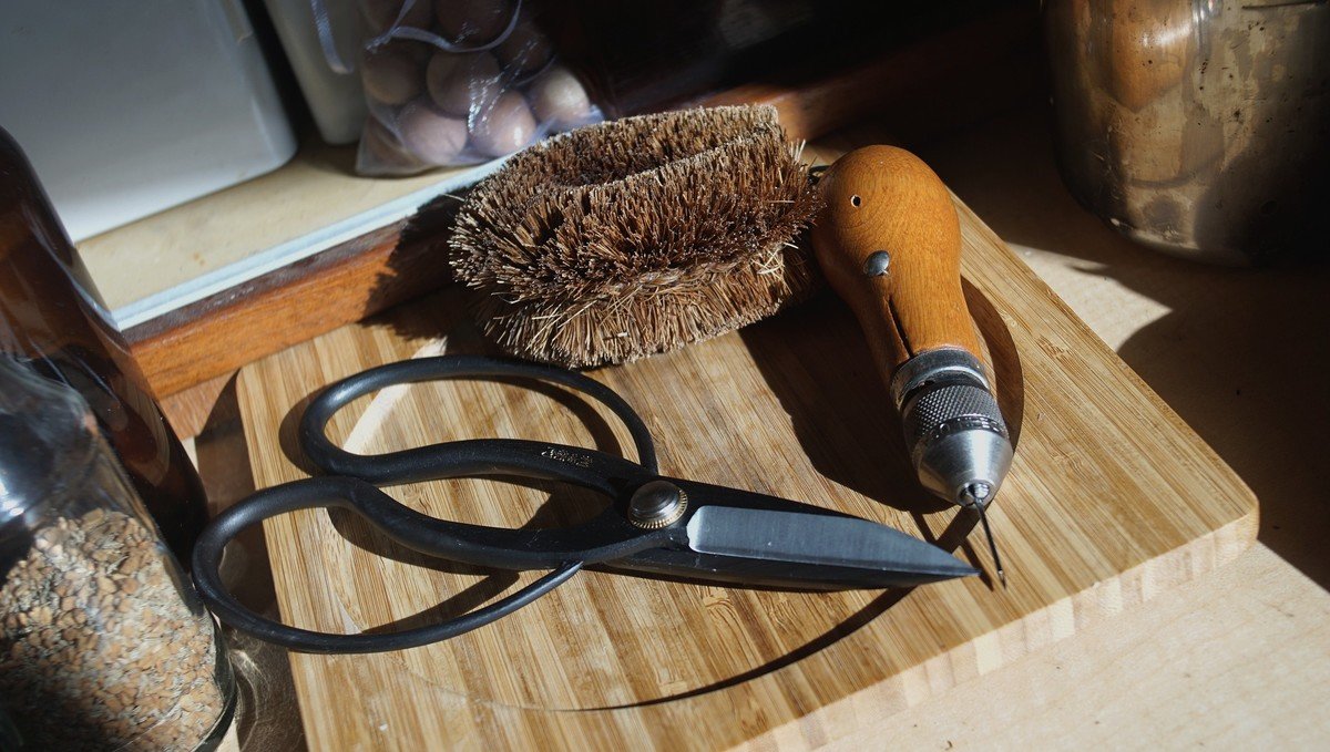 A photo of a tawashi, a sewing awl and a pair of large Japanese-style shears laying on a countertop