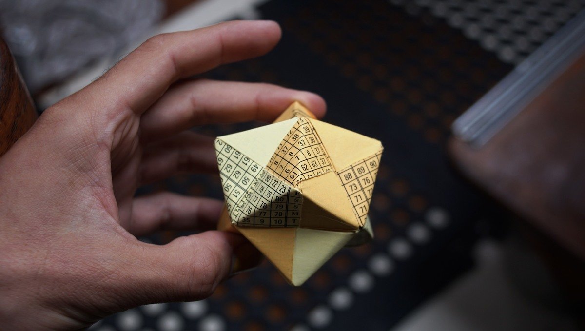 A hand holding a sonobe-origami made from old chart tables
