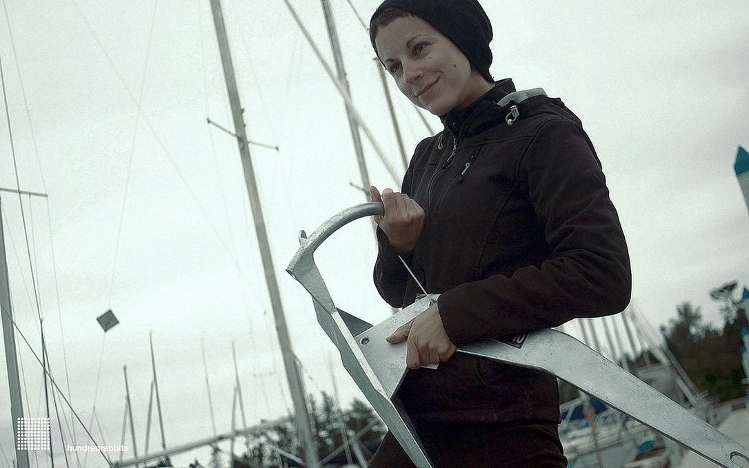 A photo of a person outside in a marina, looking very pleased while holding a Rocna anchor