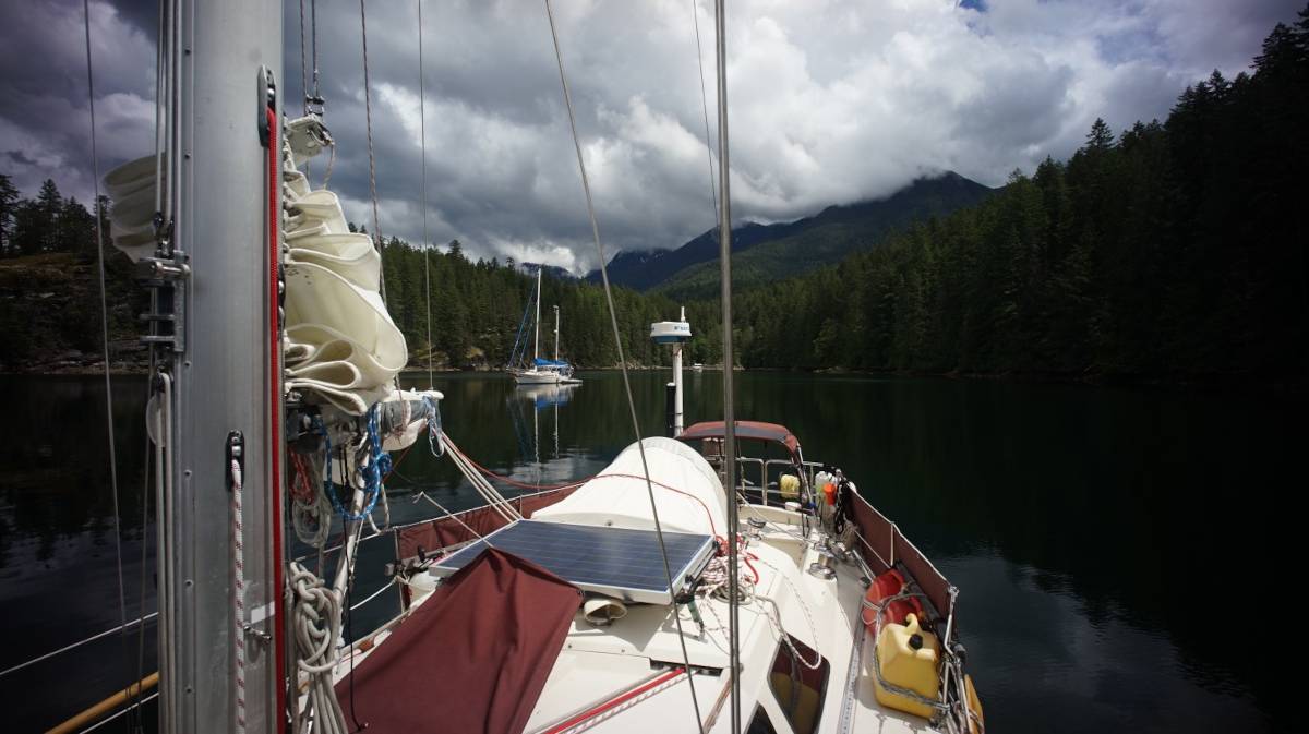 the sailboat pino at anchor in melanie cove, with a schooner in the background