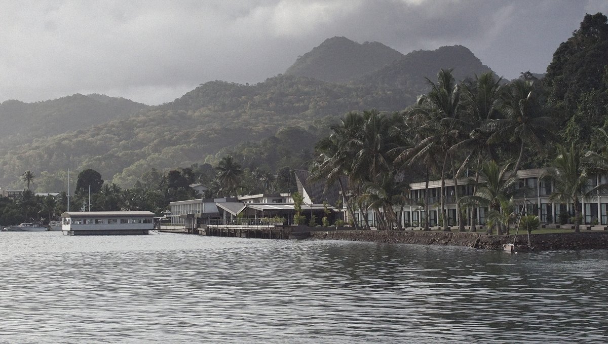 A photo of Lami Bay in Fiji, showing a hotel by the water with palm trees in the foreground