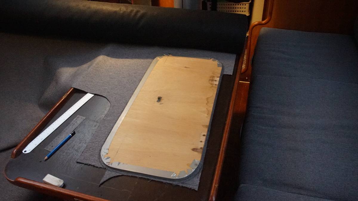 a wooden board lays over fabric, a pattern is drawn using it as a template