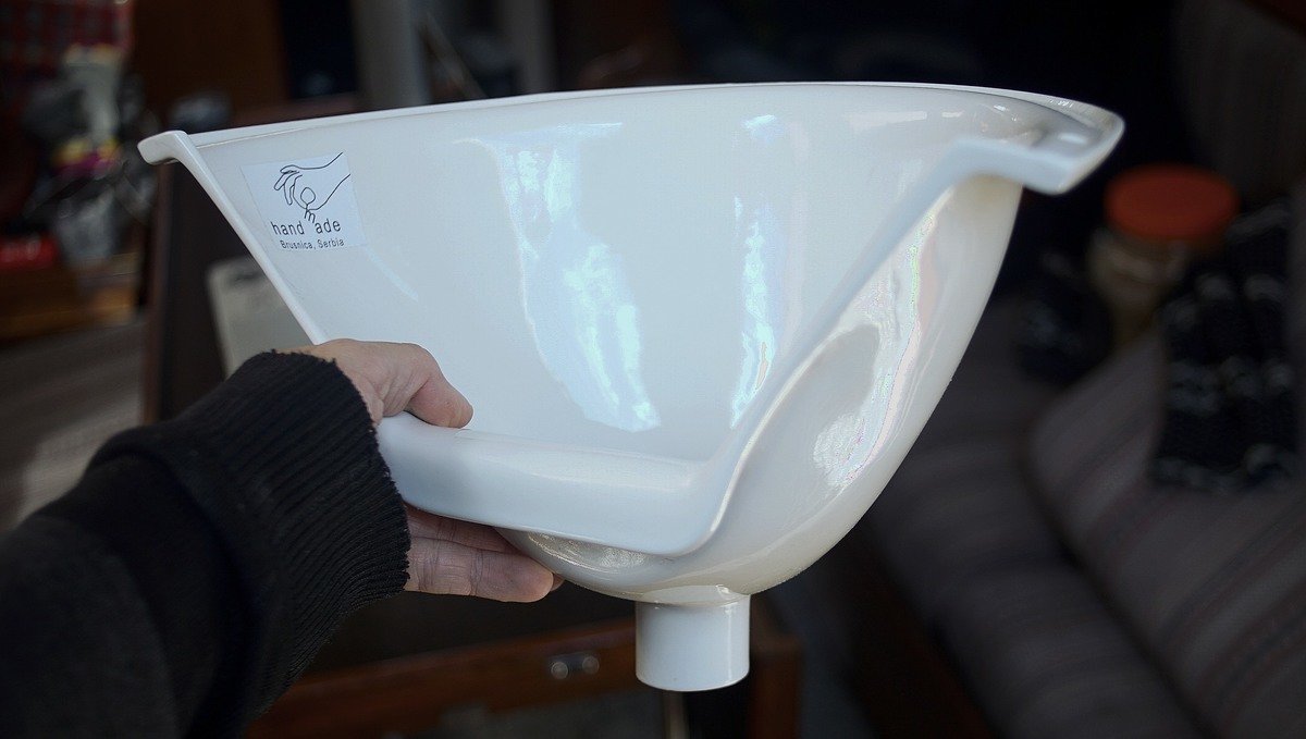 A photo of a hand holding a handmade porcelain urine separator