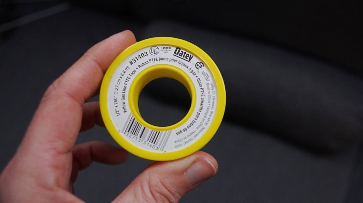 a hand holding yellow gas rated teflon tape