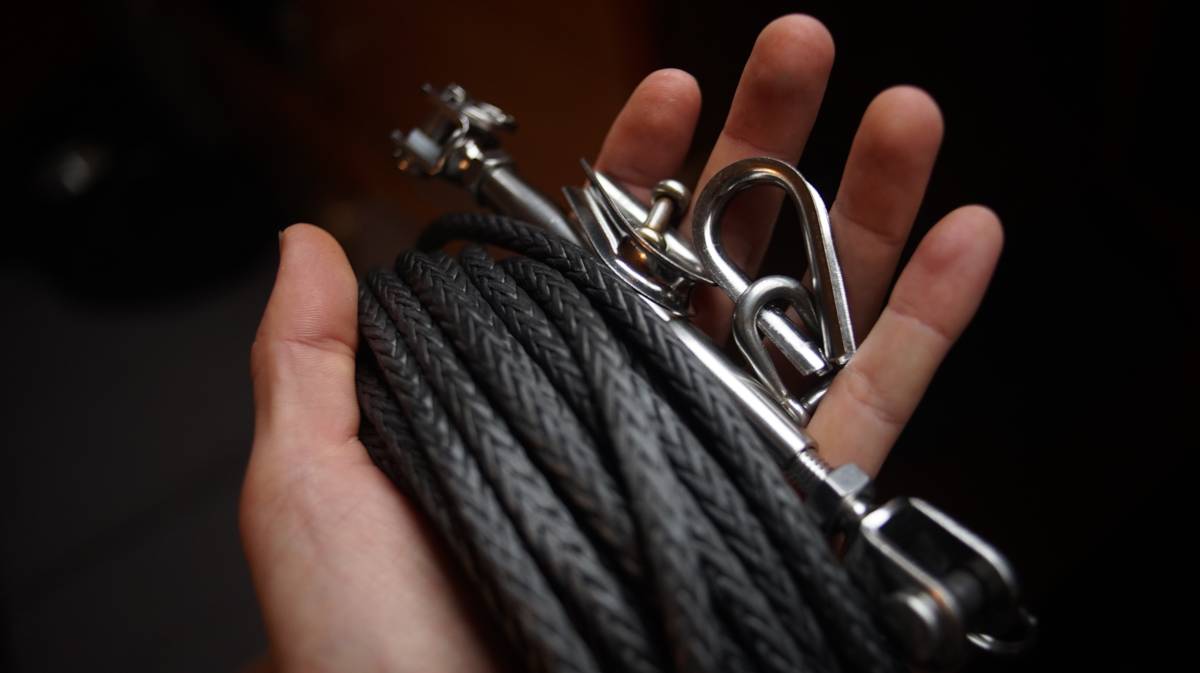 a hand holding a coil of Amsteel and some hardware