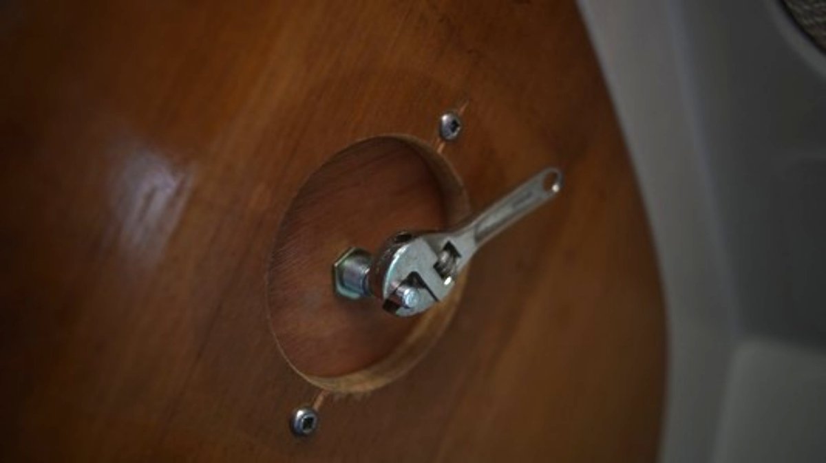 a knob sticking out a wooden wall with a tiny adjustable wrench attached to it