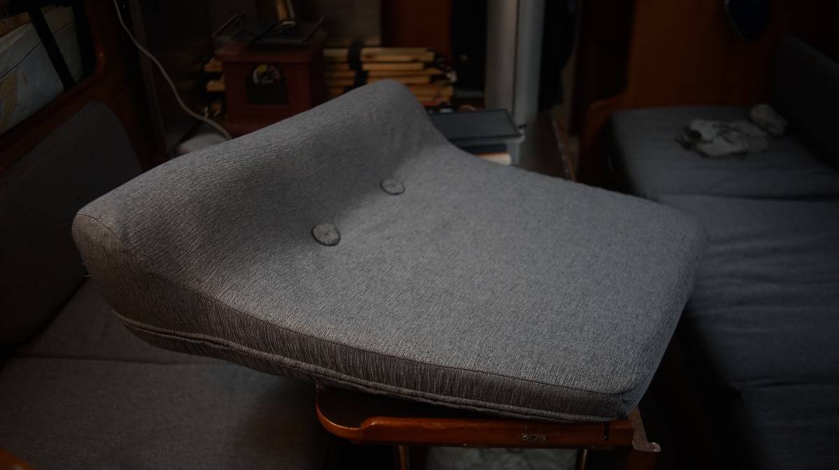 a newly-upholstered rectangular cushion with a hump, it has 2 buttons to hold the cover down firmly