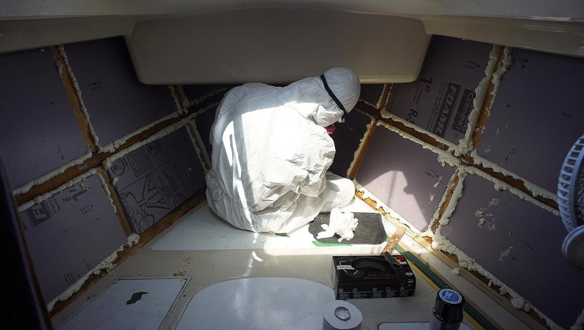 a photo of rek add spray foam in the cracks between the foam boards while wearing a protective suit and goggles