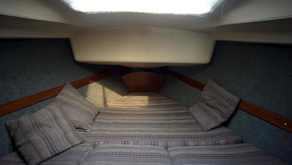 a photo of the finished insulated vberth with carpet on the walls with the cushions in place