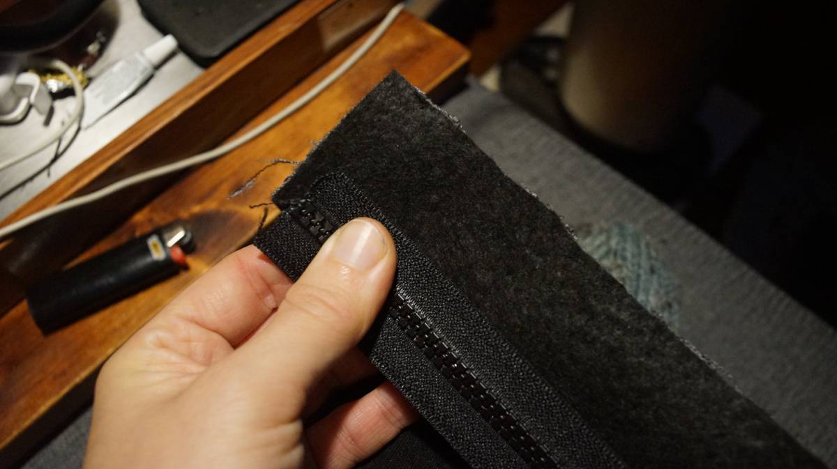 the zipper is held over the folder strip, with the middle of the teeth aligned with the fold
