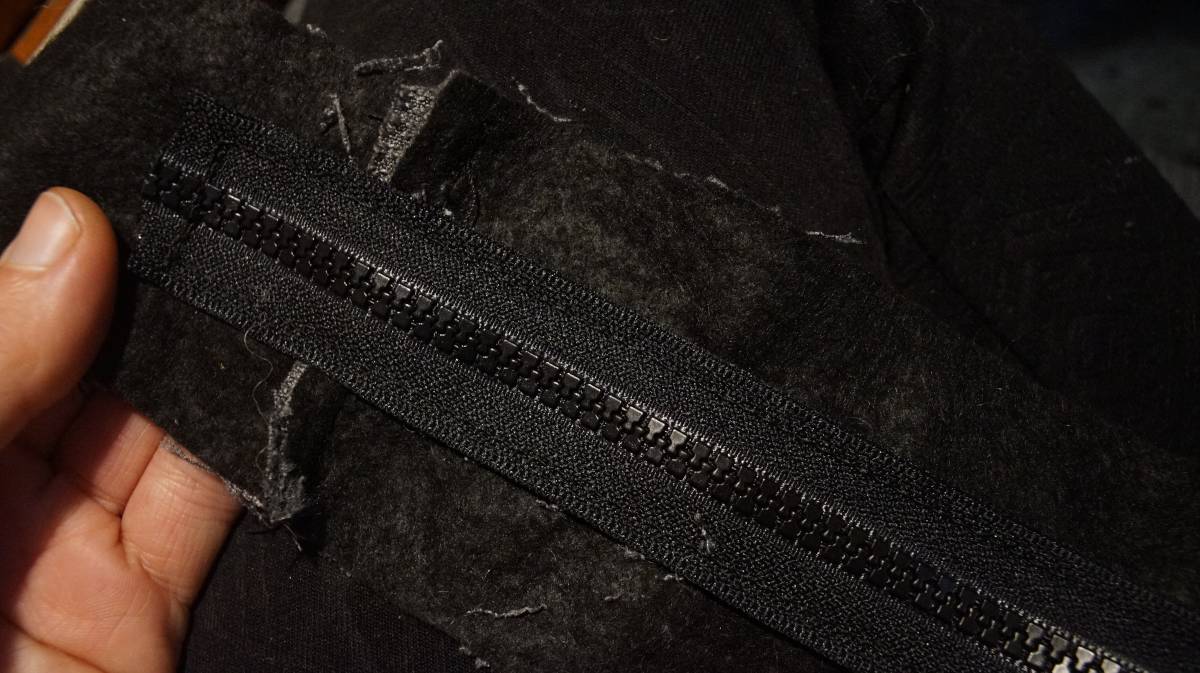 the underside of the zipper plate, showing the zipper and black underside of this non-reversible fabric