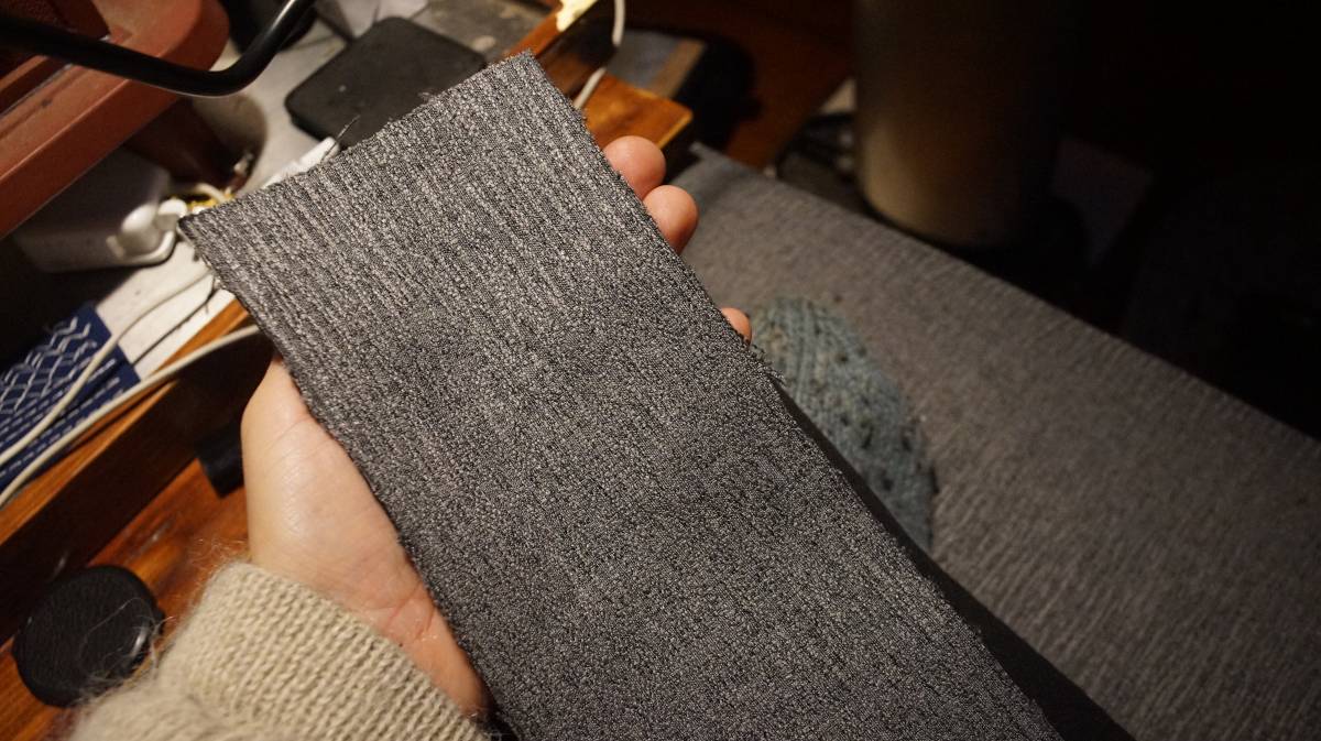 a hand holding a strip of fabric meant to hold the zipper
