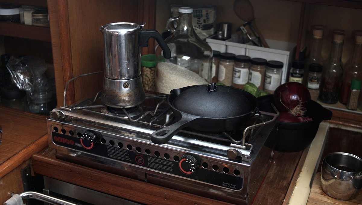 An Origo alcohol stove in a sailboat galley, there is a moka pot and a cast-iron pot overtop