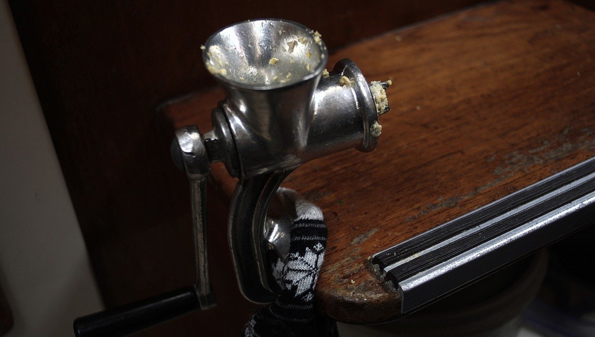 A photo of a small meat grinder attached to the step of a sailboat