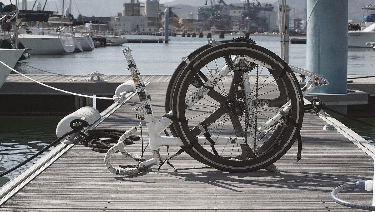 a bike on a marina dock with the two wheels off and strapped to the frame