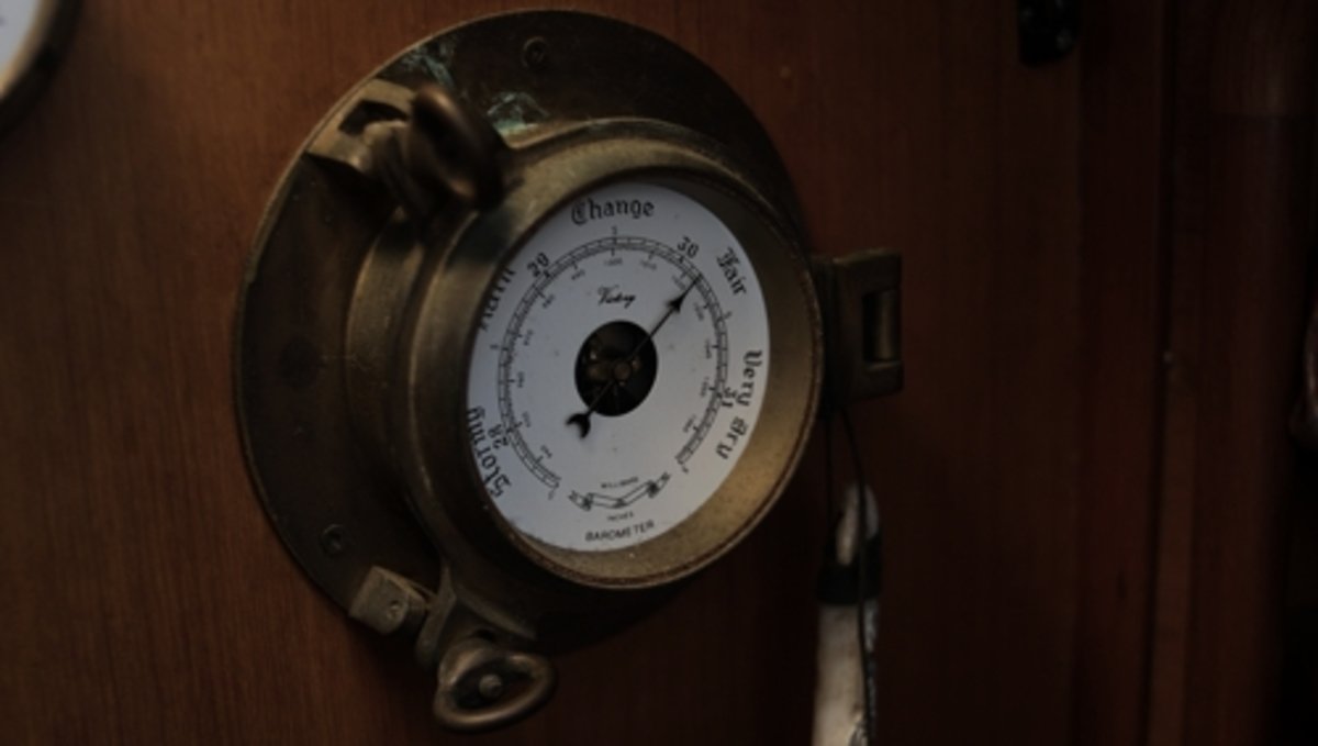 A brass barometer on a bulkhead in a sailboat