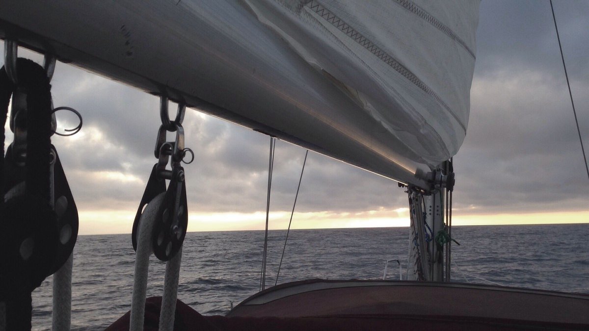 At photo from the perspective of someone standing behind a sailboat mast, staring ahead at a quiet ocean