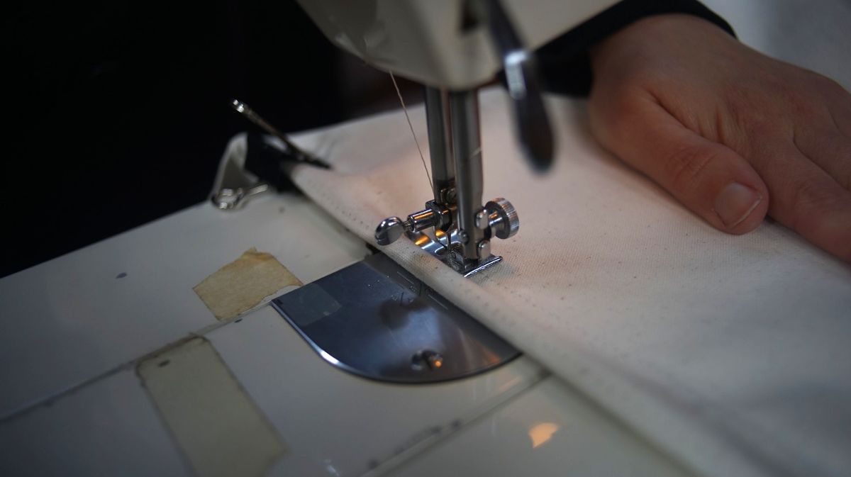 a close up of the foot of a sewing machine, working through some fabric
