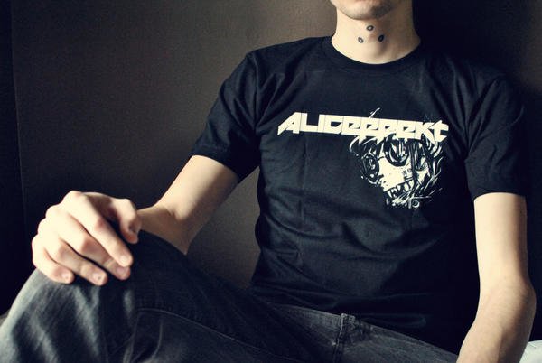 A photo from the chest down of someone posing a t-shirt with the words Aliceffekt and an illustration