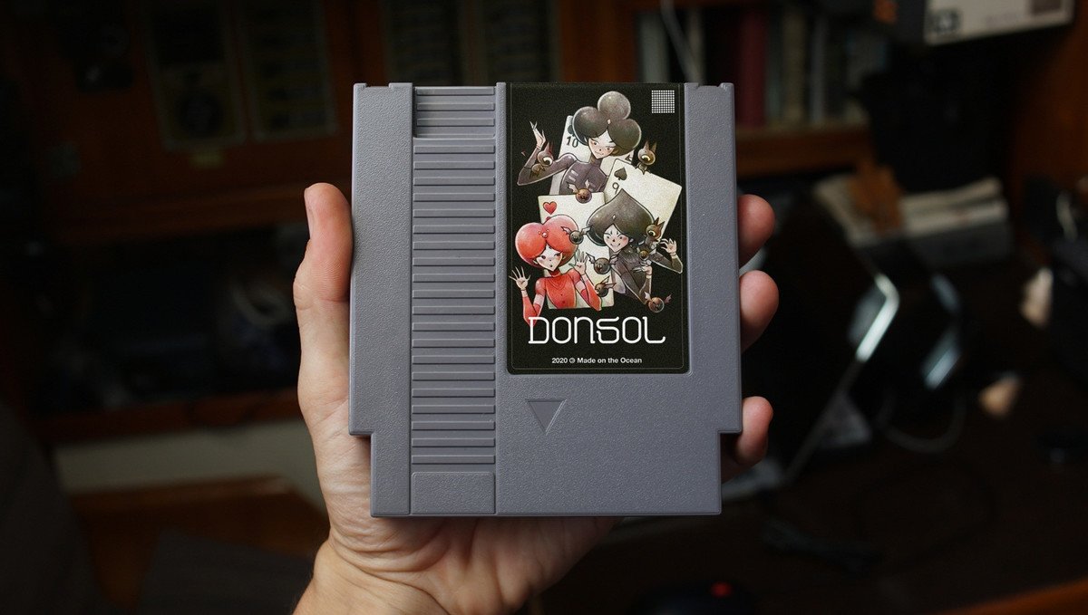 A hand holding a NES cart of the game Donsol