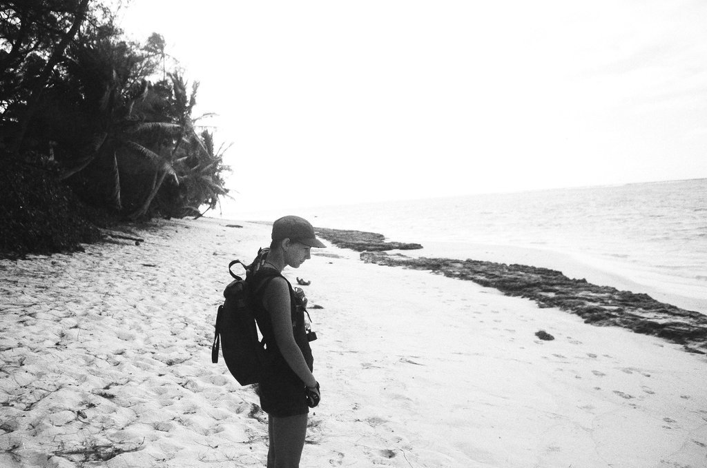 A photograph of Rek standing on the beach, appearing pensive