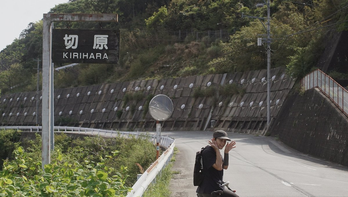 a photo of a road with rekka on a bike beneat a side reading Kirihara