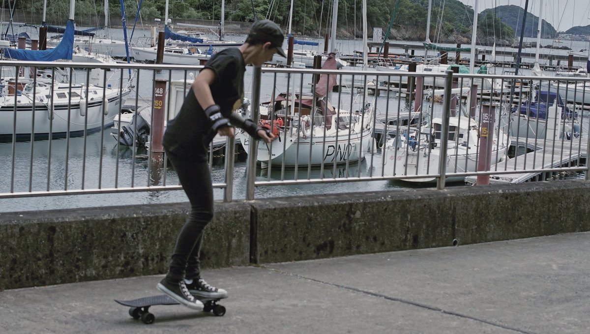 rek skateboarding in the marina parking lot with Pino moored in the background