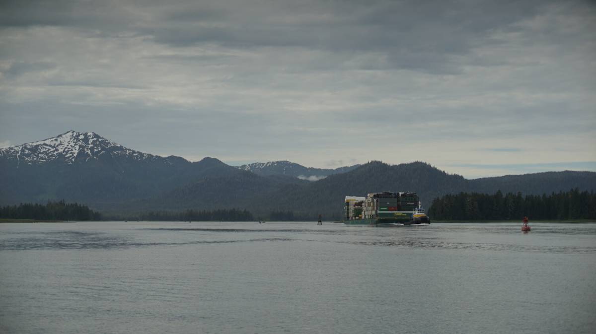 a large tugboat pulling a very large barge through wrangell narrows