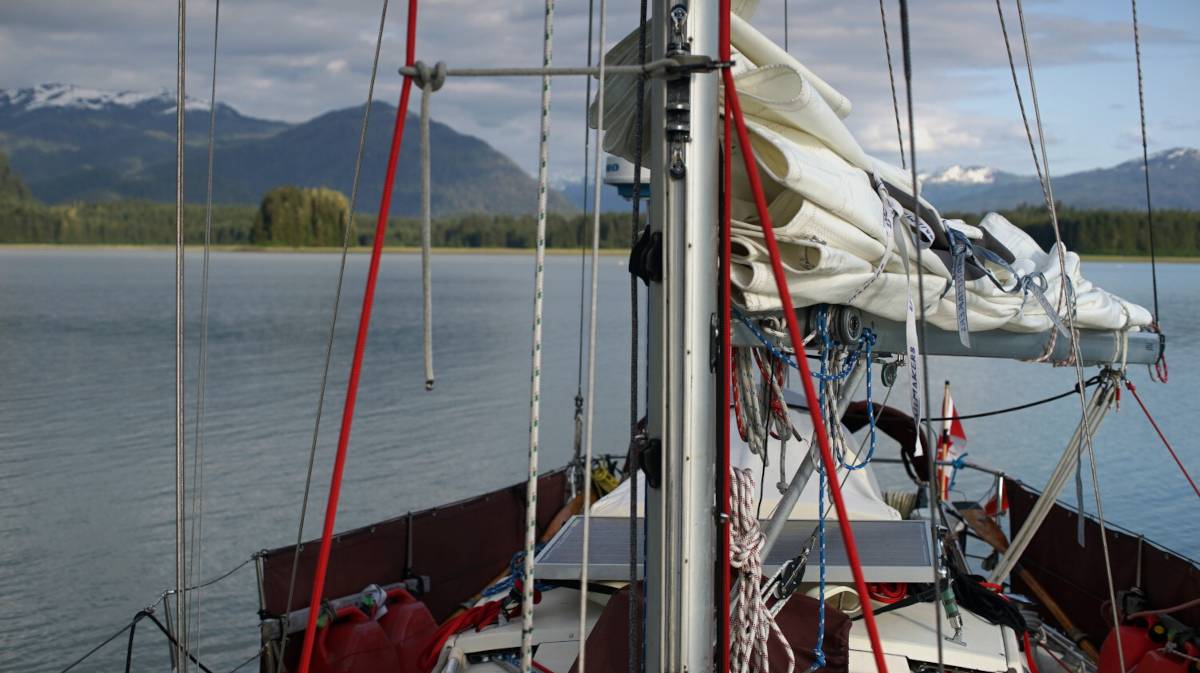 the deck of a sailboat and a calm bay visible in the background